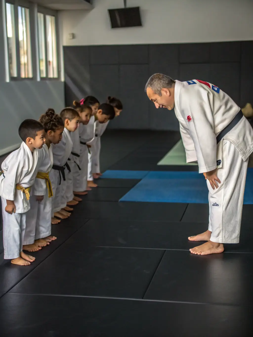 A group of young judokas bowing respectfully to their sensei before a training session, emphasizing the importance of respect in Judo Club Rochefortais.